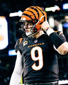 a close up of a football player wearing a helmet and holding his hand to his ear