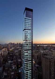 a very tall building with lots of windows in the middle of a city at sunset