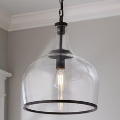 a clear glass light fixture hanging from a ceiling in a room with gray walls and white trim