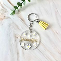 a glass keychain with daisies and the word,'jenny'on it