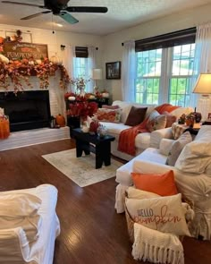 a living room filled with furniture and a fire place covered in fall decorations on top of a hard wood floor