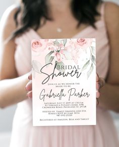 a woman holding up a pink bridal shower card