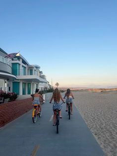 three people riding bikes down a sidewalk next to houses