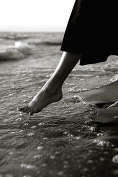 a person standing on top of a beach next to the ocean with their feet in the water