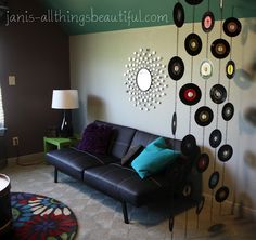 a living room filled with furniture and lots of records hanging on the wall next to a lamp