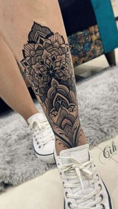 a woman's leg with a tattoo on it and an intricate flower in the center