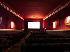 an empty theater with rows of seats facing the screen