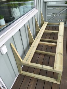 a wooden bench sitting on top of a hard wood floor next to a window with potted plants