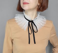 White Victorian ruffle tulle collar for parties, holidays, and themed events. A white neck ruff is a polka dot with a black velour ribbon.  The mobile accessory will instantly change the character of the image.  Even a simple dress turns into a piece of design art. The small detachable collar has unlimited possibilities. Could be a gift for her Size: 5.5 inches/ 14 cm A wonderful gift for women or female friends. The product is packed in an eco-cardboard box and is very beautifully presented. Visit our shop to see more detachable lace collars we offer: https://www.etsy.com/shop/MokushArt?section_id=31798144 Elegant Detachable Collar For Parties, Elegant Detachable Party Collar, Diy Clown Collar Ruffles, Clown Neck Ruffle, Elegant White Lace Collar, White Fitted Detachable Collar, Victorian Ruffle Collar, Tulle Collar, Clown Collar