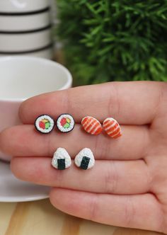 miniature sushi pins in the palm of someone's hand next to a cup