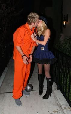 a man in an orange jumpsuit kissing a woman on the cheek while standing next to a fence