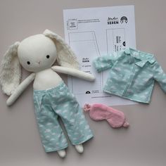 a stuffed animal doll next to two pajamas and a paper with sewing instructions on it