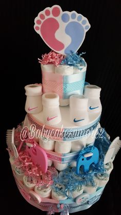 a baby shower cake with pink, blue and white items on it's tier