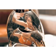 a woman in an orange dress is reflected in a mirror with her reflection on it