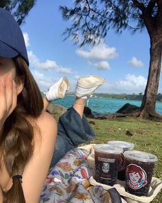 a woman laying on top of a blanket next to two cups of ice creams