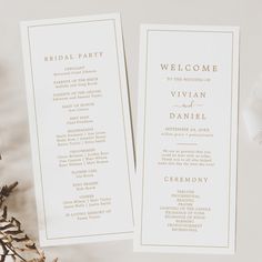 two white wedding programs with gold foil on them next to pine cones and greenery