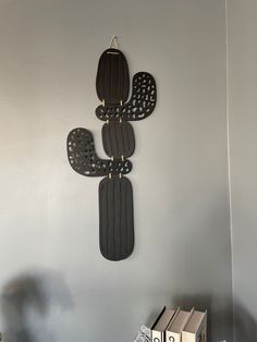 a metal cactus clock mounted to the side of a wall next to a bookshelf