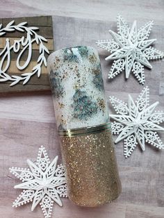 some snowflakes are laying on a table next to a glass jar with glitter