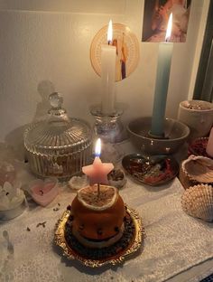 a cake with a lit candle on it sitting on a table next to other items