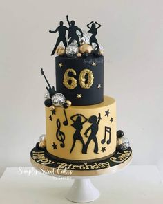 a three tiered cake with music themed decorations on the top and bottom layer is black, gold and white