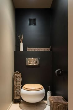 a toilet in a bathroom with black walls and white fixtures on the wall, next to a wicker basket