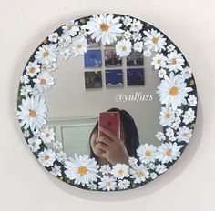 a woman taking a selfie in front of a mirror with daisies on it