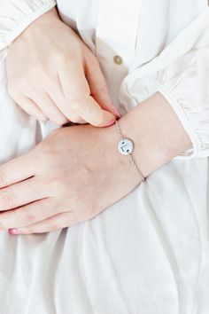 a woman wearing a white shirt holding onto a bracelet with a smiley face on it