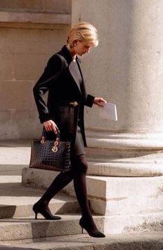 a woman walking down the street carrying a purse