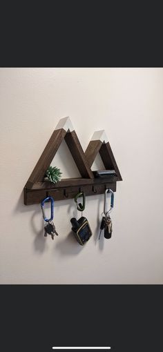 a wooden shelf with key hooks hanging from it's sides and two triangle shaped shelves on the wall