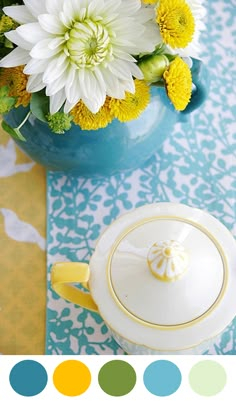 there is a teapot with yellow and white flowers in it