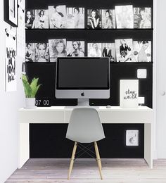 a desk with a computer on it in front of a black and white photo wall