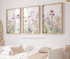 three paintings on the wall above a bed in a room with white sheets and pillows