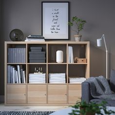 a living room with a book shelf filled with books next to a gray couch and potted plant