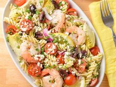 pasta salad with shrimp, tomatoes, olives and fettuccine in a white bowl