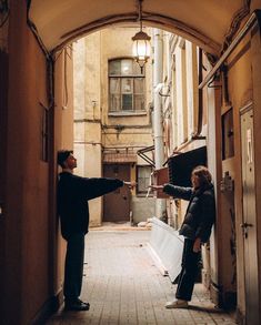 two people standing in an alley pointing at each other