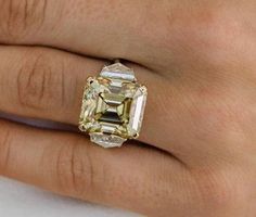 a woman's hand with a yellow and white diamond ring on top of it