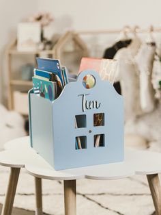 there is a blue toy house with books in it on the table next to a chair