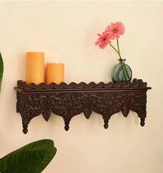 a wooden shelf with candles and flowers on it