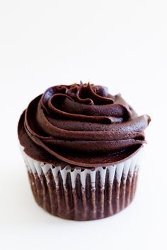 a cupcake with chocolate frosting sitting on a white surface