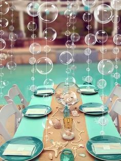 the table is set with plates and place settings for an outdoor dinner by the pool