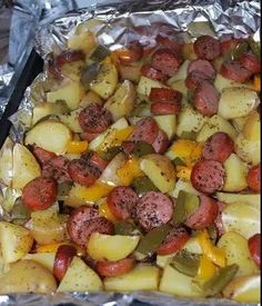 a tray filled with potatoes and sausages on top of tin foil