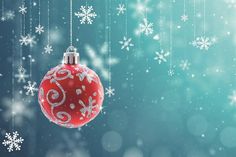 a red ornament hanging from a string with snowflakes in the background