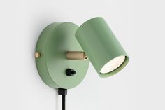 a green wall light with two lights on it's sides and a black cord