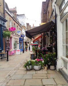 the sidewalk is lined with potted plants and flower boxes on it's sides