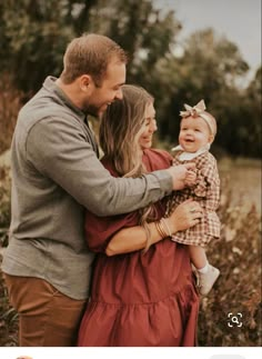 a man and woman holding a baby in their arms while standing next to each other