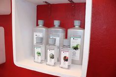 three bottles of hand soap are on the shelf next to each other in front of a red wall