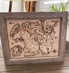 a wooden frame that has a map in it on top of a table next to a potted plant