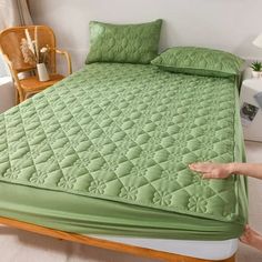 a bed with green sheets and pillows in a room