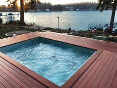 a hot tub sitting on top of a wooden deck next to a body of water