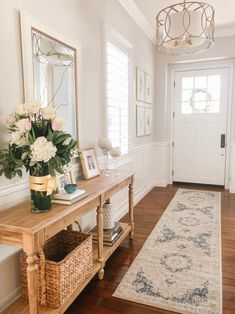 a hallway with a rug, mirror and flowers on the table in front of it